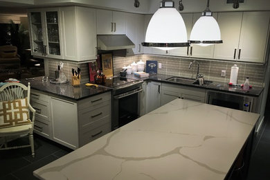 Mid-sized minimalist l-shaped cement tile floor eat-in kitchen photo in Edmonton with a double-bowl sink, shaker cabinets, white cabinets, granite countertops, gray backsplash, cement tile backsplash, stainless steel appliances and an island