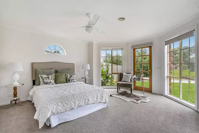 This is an example of a large transitional master bedroom in Melbourne with white walls, carpet and grey floor.