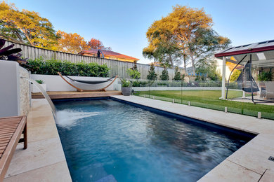 Photo of a mid-sized contemporary backyard rectangular lap pool in Sydney with a water feature and natural stone pavers.