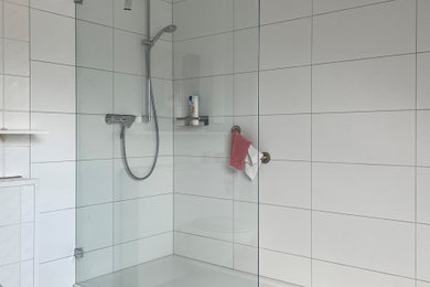 Imagen de cuarto de baño contemporáneo grande con baldosas y/o azulejos blancos, baldosas y/o azulejos de porcelana, paredes blancas, suelo de baldosas de porcelana, aseo y ducha, suelo negro y ducha abierta