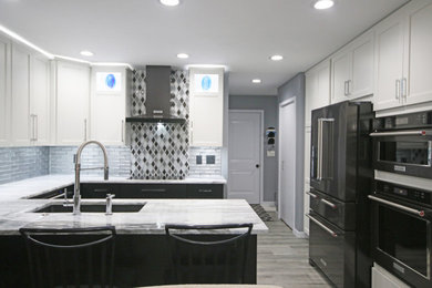 Inspiration for a contemporary kitchen/diner in Grand Rapids with a submerged sink, shaker cabinets, black appliances, a breakfast bar and grey floors.