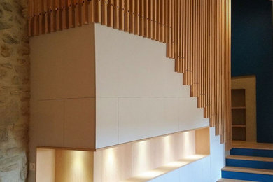Cette photo montre un grand escalier peint moderne en U et bois avec des marches en bois, un garde-corps en bois et rangements.
