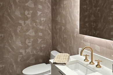 Modern inredning av ett litet toalett, med släta luckor, vita skåp, en bidé, rosa kakel, rosa väggar, klinkergolv i porslin, ett nedsänkt handfat, bänkskiva i kalksten och vitt golv