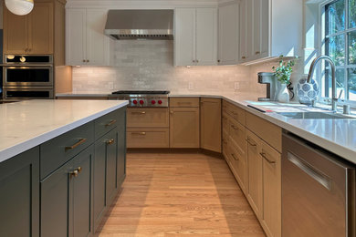Photo of a large transitional l-shaped eat-in kitchen in San Francisco with an undermount sink, shaker cabinets, light wood cabinets, quartz benchtops, white splashback, subway tile splashback, stainless steel appliances, light hardwood floors, with island, brown floor and white benchtop.