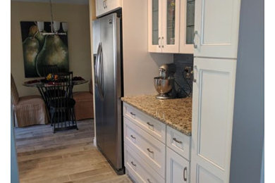 Eat-in kitchen - contemporary eat-in kitchen idea in New York with an undermount sink, granite countertops, gray backsplash, glass tile backsplash, stainless steel appliances and an island