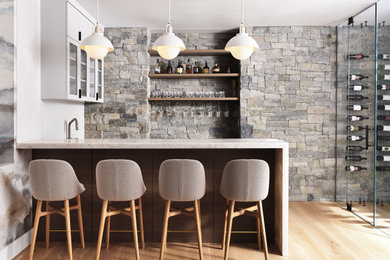 Home bar - medium tone wood floor home bar idea in San Francisco with marble countertops, white backsplash and ceramic backsplash