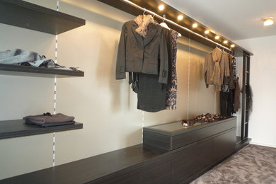 Mid-sized contemporary women's dressing room in Frankfurt with flat-panel cabinets, dark wood cabinets, carpet and grey floor.