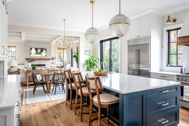 Eat-in kitchen - large contemporary u-shaped medium tone wood floor and brown floor eat-in kitchen idea in DC Metro with an undermount sink, shaker cabinets, blue cabinets, quartz countertops, white backsplash, quartz backsplash, stainless steel appliances, an island and white countertops