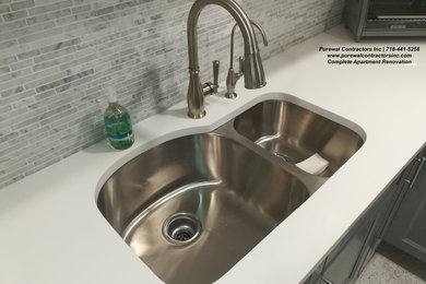 Large transitional l-shaped porcelain tile and white floor eat-in kitchen photo in New York with a double-bowl sink, shaker cabinets, white cabinets, quartz countertops, gray backsplash, glass sheet backsplash, stainless steel appliances, no island and white countertops