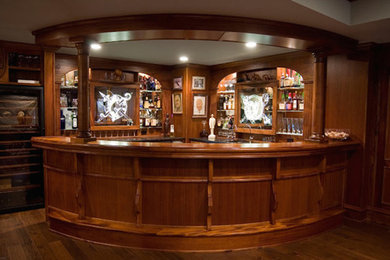 Example of a large classic l-shaped brown floor seated home bar design in Other with open cabinets, medium tone wood cabinets, wood countertops and mirror backsplash