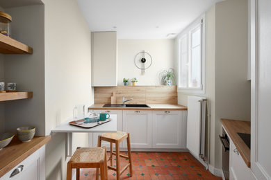 Aménagement d'une cuisine moderne en L fermée et de taille moyenne avec une crédence en bois et un sol rouge.