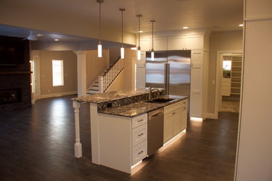 Enclosed kitchen - mid-sized transitional medium tone wood floor and gray floor enclosed kitchen idea in Other with a double-bowl sink, recessed-panel cabinets, white cabinets, granite countertops, stainless steel appliances and an island