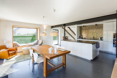 Large contemporary galley open plan kitchen in Munich with a drop-in sink, flat-panel cabinets, white cabinets, yellow splashback, black appliances, vinyl floors, multiple islands and grey floor.