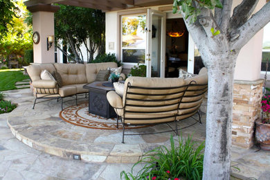 Small tuscan backyard stone patio photo in Orange County with a fire pit and a roof extension