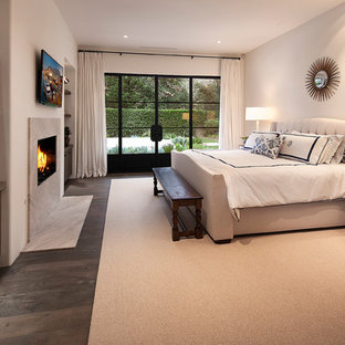 Inredning av ett modernt stort sovrum, med vita väggar, heltäckningsmatta, en standard öppen spis och en spiselkrans i sten