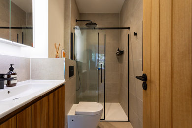 This is an example of a small victorian grey and brown bathroom in London with beaded cabinets, medium wood cabinets, a built-in shower, a wall mounted toilet, white tiles, cement tiles, white walls, cement flooring, a built-in sink, granite worktops, grey floors, a sliding door, white worktops, a wall niche, a single sink, a built in vanity unit and a drop ceiling.