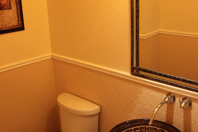 Small elegant light wood floor powder room photo in Toronto with furniture-like cabinets, medium tone wood cabinets, a two-piece toilet, beige walls, a vessel sink and wood countertops