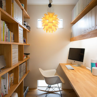 Idéer för funkis hemmabibliotek, med vita väggar, mellanmörkt trägolv, ett inbyggt skrivbord och brunt golv