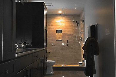 Corner shower - large traditional master gray tile and porcelain tile porcelain tile corner shower idea in Chicago with raised-panel cabinets, brown cabinets, a two-piece toilet, beige walls, an undermount sink and granite countertops