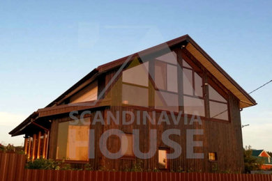 Стильный дизайн: двухэтажный, коричневый частный загородный дом среднего размера в скандинавском стиле с двускатной крышей, металлической крышей и коричневой крышей - последний тренд