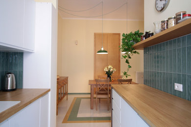 Imagen de cocina comedor contemporánea pequeña sin isla con armarios con paneles lisos, puertas de armario blancas, encimera de madera, salpicadero gris y salpicadero de azulejos en listel