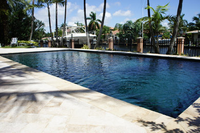 This is an example of a large traditional backyard rectangular lap pool in Miami with tile.