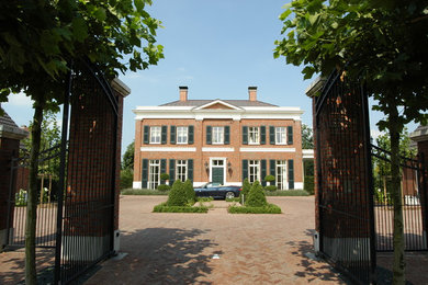 Mittelgroßes, Zweistöckiges Klassisches Haus mit Backsteinfassade, roter Fassadenfarbe und Walmdach in Düsseldorf