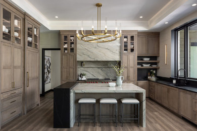 Open concept kitchen - large farmhouse u-shaped medium tone wood floor, brown floor and tray ceiling open concept kitchen idea in Detroit with an undermount sink, flat-panel cabinets, medium tone wood cabinets, quartzite countertops, gray backsplash, quartz backsplash, paneled appliances, an island and gray countertops