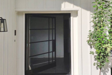 Imagen de puerta principal actual de tamaño medio con paredes blancas, suelo de ladrillo, puerta pivotante, puerta negra y suelo rojo