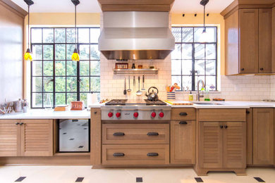 Example of a transitional l-shaped porcelain tile and white floor enclosed kitchen design in Portland with an undermount sink, shaker cabinets, light wood cabinets, solid surface countertops, white backsplash, ceramic backsplash, stainless steel appliances, an island and white countertops
