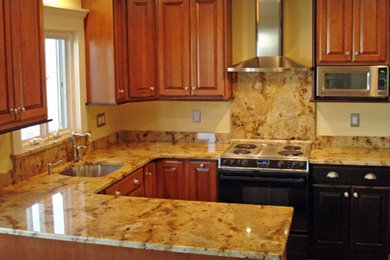 Example of a mid-sized classic dark wood floor kitchen design in Houston with a drop-in sink, raised-panel cabinets, medium tone wood cabinets, granite countertops, beige backsplash, terra-cotta backsplash and stainless steel appliances