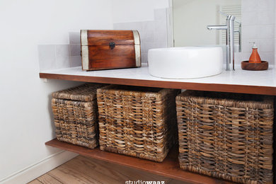 Cette photo montre une salle de bain exotique avec des carreaux de céramique, un mur blanc, parquet clair, un lavabo posé et un plan de toilette en carrelage.