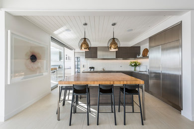 Design ideas for a contemporary l-shaped kitchen in Christchurch with an integrated sink, dark wood cabinets, stainless steel benchtops, white splashback, ceramic splashback, stainless steel appliances and with island.