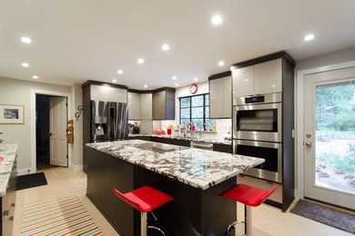 Example of a large trendy l-shaped medium tone wood floor and beige floor enclosed kitchen design in New York with an undermount sink, flat-panel cabinets, gray cabinets, granite countertops, white backsplash, glass tile backsplash, stainless steel appliances and an island