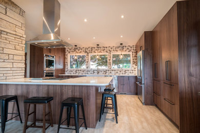 This is an example of a large midcentury l-shaped eat-in kitchen in Seattle with a farmhouse sink, flat-panel cabinets, dark wood cabinets, quartz benchtops, beige splashback, mosaic tile splashback, stainless steel appliances, porcelain floors, a peninsula and beige floor.