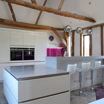 Contemporary kitchen by John Ladbury-  pink splash-back. Barn conversion