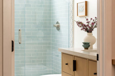 Alcove shower - coastal 3/4 turquoise tile and subway tile beige floor and single-sink alcove shower idea in San Diego with flat-panel cabinets, light wood cabinets, white walls, an undermount sink, beige countertops and a freestanding vanity
