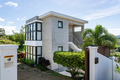 Minimalist gray three-story concrete exterior home photo in Other with a white roof