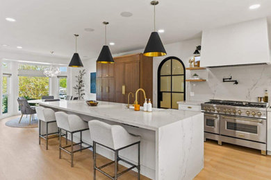 Example of a huge minimalist l-shaped medium tone wood floor and brown floor eat-in kitchen design in San Diego with an undermount sink, shaker cabinets, white cabinets, quartzite countertops, white backsplash, stone slab backsplash, stainless steel appliances, an island and white countertops