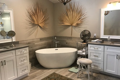 Example of a large transitional master vinyl floor and brown floor bathroom design in Tampa with shaker cabinets, white cabinets, a two-piece toilet, gray walls, an undermount sink, quartz countertops, a hinged shower door and gray countertops