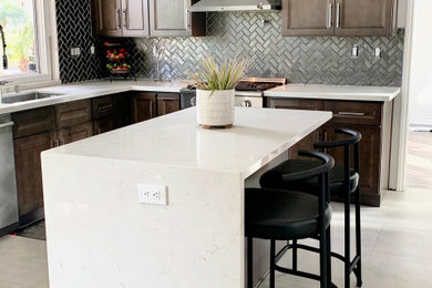 Example of a mid-sized transitional u-shaped porcelain tile and beige floor kitchen design in Orange County with an undermount sink, raised-panel cabinets, quartzite countertops, gray backsplash, ceramic backsplash, stainless steel appliances, an island and white countertops