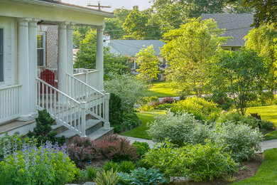 Photo of a mid-sized traditional partial sun front yard stone water fountain landscape in DC Metro for spring.