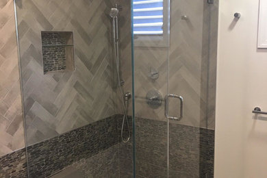Minimalist master gray tile corner shower photo in New York with white walls and a hinged shower door