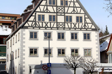 Großes, Dreistöckiges Klassisches Haus mit Betonfassade, weißer Fassadenfarbe und Satteldach in Sonstige