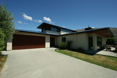 Photo of a mid-sized contemporary two-storey beige exterior in Dunedin with mixed siding and a hip roof.