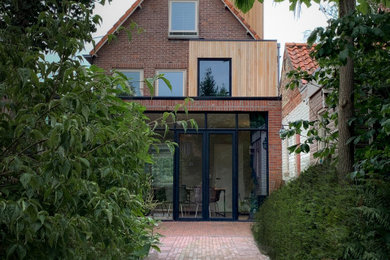 Inspiration for a medium sized and red contemporary rear house exterior in Other with three floors, wood cladding, a pitched roof, a tiled roof, a red roof and board and batten cladding.