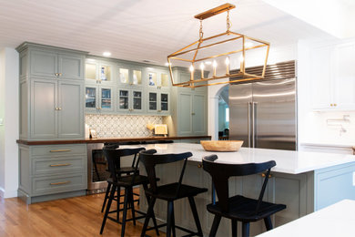 Inspiration for a huge timeless u-shaped light wood floor, brown floor and shiplap ceiling eat-in kitchen remodel in Boston with a farmhouse sink, flat-panel cabinets, green cabinets, quartz countertops, green backsplash, marble backsplash, stainless steel appliances, two islands and white countertops