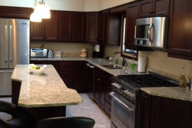 Example of a transitional porcelain tile eat-in kitchen design in Other with a double-bowl sink, recessed-panel cabinets, brown cabinets, granite countertops, beige backsplash, stone slab backsplash, stainless steel appliances and an island