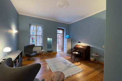 Mittelgroßes Nordisches Arbeitszimmer mit Arbeitsplatz, blauer Wandfarbe, braunem Holzboden, freistehendem Schreibtisch und braunem Boden in Berlin