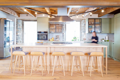 Inspiration for a large country l-shaped light wood floor and exposed beam kitchen remodel in Montreal with a farmhouse sink, shaker cabinets, green cabinets, stainless steel appliances, an island and white countertops